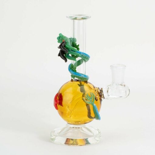 The Empire Glassworks Dragon Sphere Mini-Tube is a glass pipe with a round amber base, clear neck, and a blue-green dragon wrapped around it, plus a side chamber and clear circular foot.