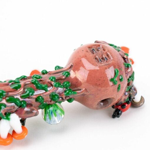 A close-up of the Empire Glassworks Bug's Life Small Spoon Pipe, designed to resemble a tree branch with textured brown, green, and orange details and a round central bowl.