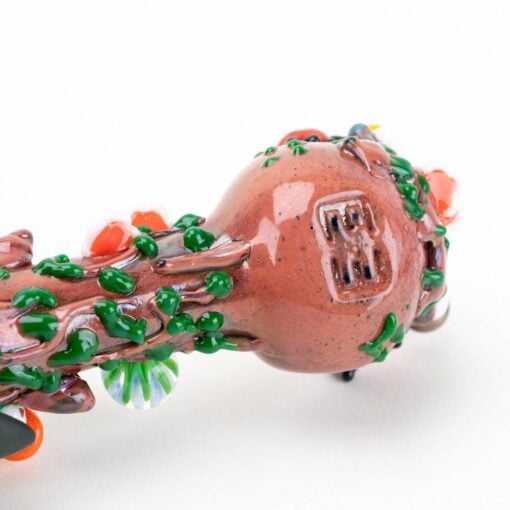 A close-up of the Empire Glassworks Bug's Life Small Spoon Pipe shows its brown, round body with green and red textured accents, a raised BB mark, and intricate, colorful glass details inspired by Bug's Life.