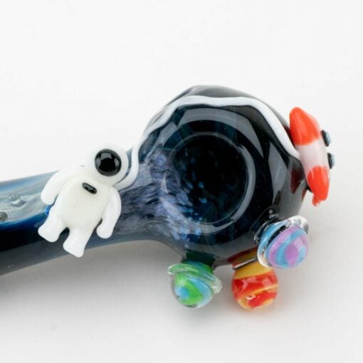 The Empire Glassworks Galactic Spoon Pipe showcases a small white astronaut, vibrant planets, and a red rocket ship—all displayed against a cosmic dark background.