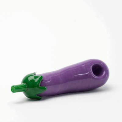 The Empire Glassworks Dry Pipe - Eggplant features a vibrant purple body with a green stem, beautifully crafted to resemble an eggplant and displayed on a white background.