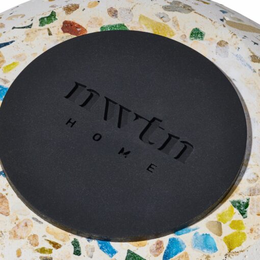 Close-up of a round NWTN Home Symi Ashtray featuring a terrazzo-style surface with multicolored specks and a black center engraved with "nwtm HOME.