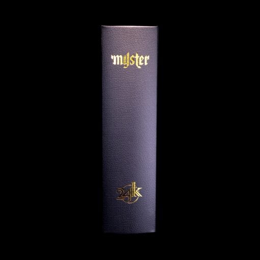 A dark, leather-bound 24k Stashtray Bundle stands upright against a black background, its spine adorned with "mystery" in ornate gold at the top and the gold 24k Stashtray symbol near the bottom.