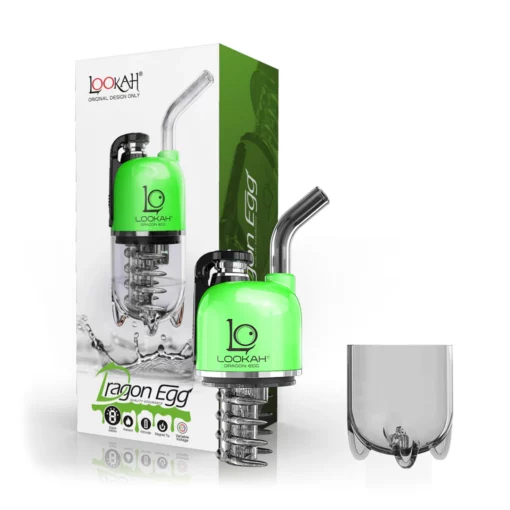 A green and clear glass water pipe, the Lookah Dragon Egg vaporizer in Spatter Black-Green, is shown beside its packaging box displaying the same product image and logo. A separate clear component sits nearby.