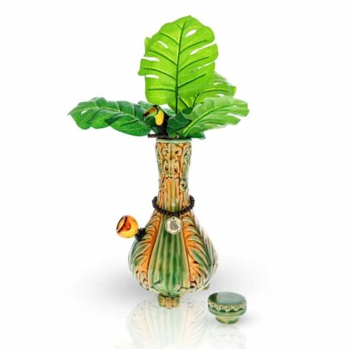The TocaCabana Vase Bong features a tropical jungle plant design with large green leaves at the top and a small container on the side, all set against a white background.