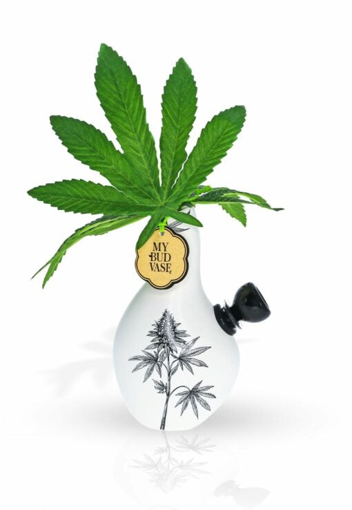 The Love Bud Vase Bong is a white vase bong with a black cannabis leaf design, green cannabis leaves inside, a small black side attachment, and a “MY BUD VASE” tag hanging from the neck.