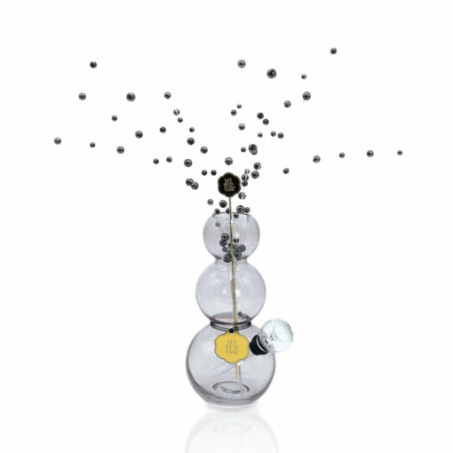 The Bubbles Vase Bong features three stacked glass spheres, reminiscent of bubbles, topped with a clear stopper and adorned with a decorative gold label and artistic black bead accents.