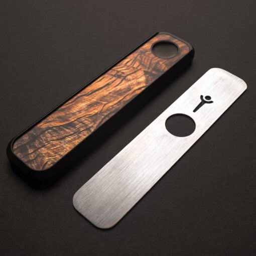 The High Roller Mahogany Genius Pipe, rectangular with a textured wooden top and separate brushed metal cover, features a circular cutout and keyhole symbol, displayed on a dark surface.