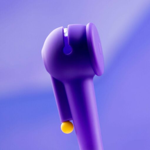 A close-up of The Pipe - Grape, a grape-purple wireless earbud with a small yellow accent, set against a soft purple background.