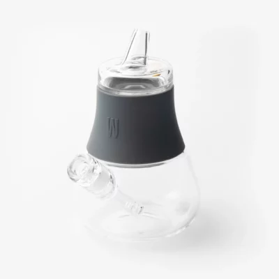 The Bubbler - Smoke features clear glass, a black silicone sleeve around the neck, and a glass mouthpiece. Photographed on a white background, this modern bubbler offers smooth smoke in style.