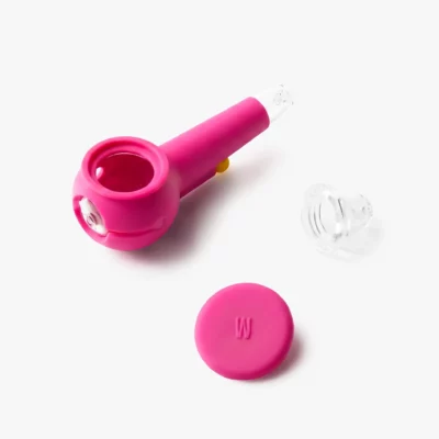 The Pipe - Hot Pink is a silicone smoking pipe with a round bowl, matching lid, and clear glass attachment. Displayed on a white background, it brings a vibrant pop of color to your collection.