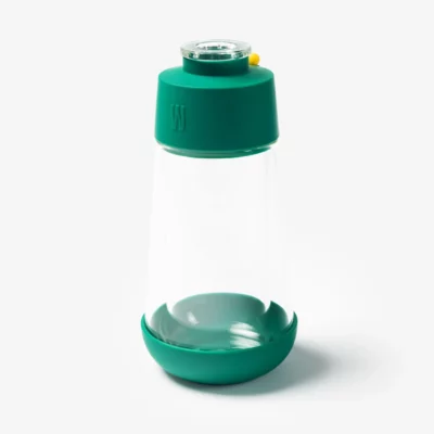 The Gravity Bong - Forest features clear glass, a wide base, green plastic lid and bottom, plus a small yellow button on the lid, all shown against a plain white background.