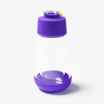 The Gravity Bong - Grape features a clear glass container with a grape-colored silicone lid and base, plus a small yellow tab on the lid. Set against a plain white background, it’s ideal for creative gravity bong enthusiasts.