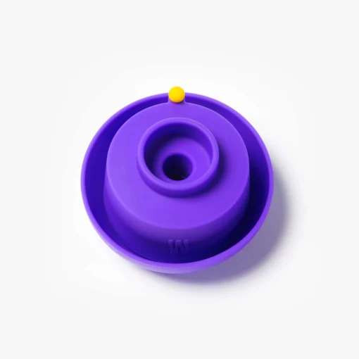 The Gravity Bong - Grape: a round, grape-colored silicone piece with a central hole and a small yellow knob on its rim, displayed against a white background.