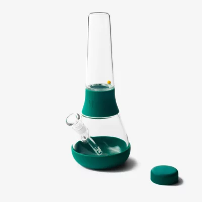 The Bong - Forest features modern glass with teal silicone accents, shown upright on a white background. It includes a small glass bowl and a matching teal cap beside the pipe, evoking the serene hues of a tranquil forest.