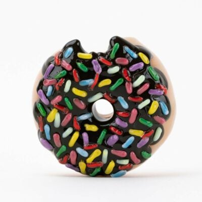 The Empire Glassworks Donut Bite Me Dry Pipe is a round donut-shaped dry pipe with chocolate glaze and colorful sprinkles, featuring a small bite on the top left edge, shown against a plain white background.