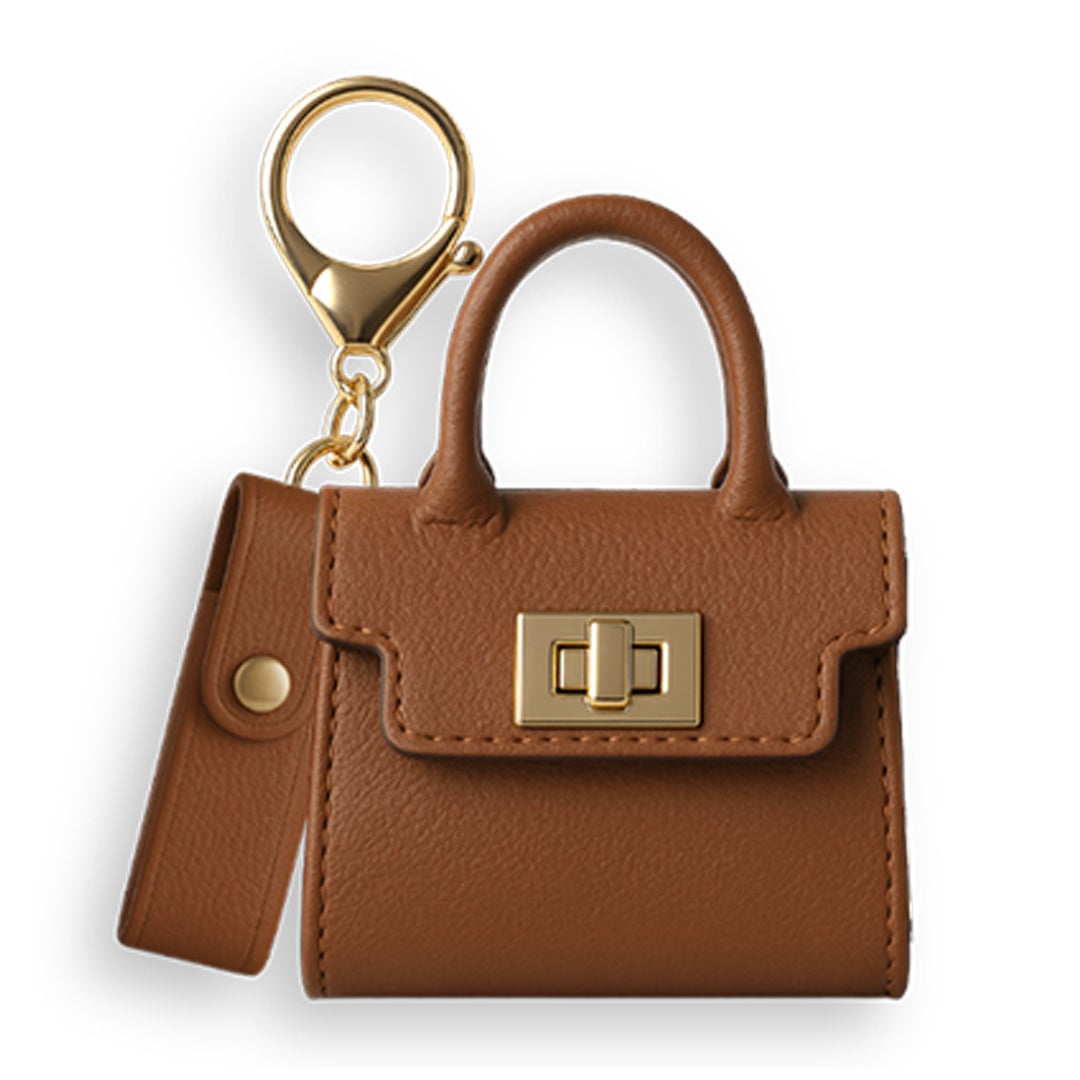 A small brown leather Penjamin Pursejamin Vaporizer keychain, shaped like a handbag with a gold clasp, handle, and snap-button strap, shown against a white background.