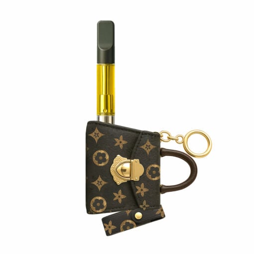 A Penjamin Pursejamin Vaporizer with a gold cartridge is partially inside a small brown designer pouch featuring gold hardware, a monogram pattern, keyring, and leather handle.