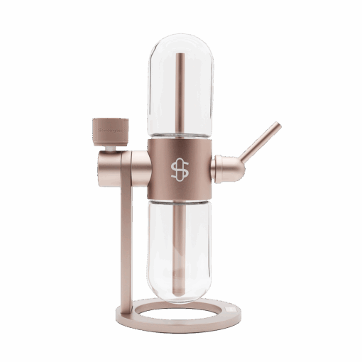 The Stündenglass Gravity Infuser - Desert Rose | 360° Gravity Hookah features a modern cylindrical rose gold and glass design with a side lever and "S" logo, displayed against a plain white background.