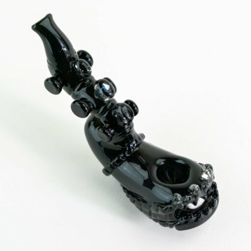 Empire Glassworks Alien Hand Pipe featuring a sculpted alien design with black glass body, white teeth details, and glow-in-the-dark beads.