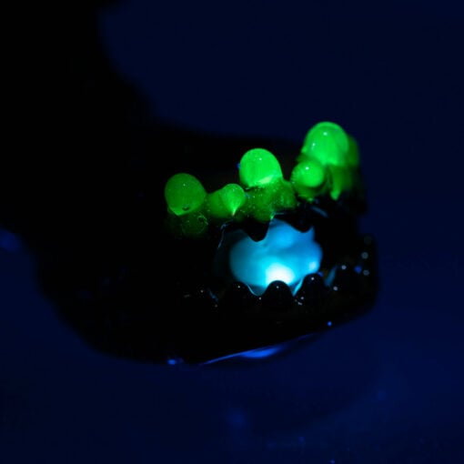Empire Glassworks Alien Hand Pipe featuring a sculpted alien design with black glass body, white teeth details, and glow-in-the-dark beads.