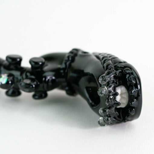 Empire Glassworks Alien Hand Pipe featuring a sculpted alien design with black glass body, white teeth details, and glow-in-the-dark beads.