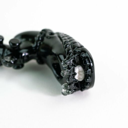 Empire Glassworks Alien Hand Pipe featuring a sculpted alien design with black glass body, white teeth details, and glow-in-the-dark beads.