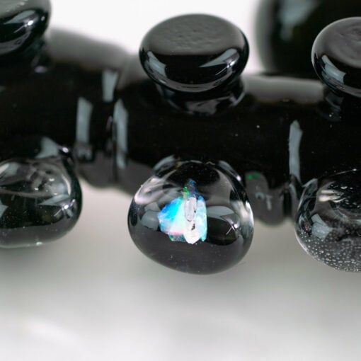 Empire Glassworks Alien Hand Pipe featuring a sculpted alien design with black glass body, white teeth details, and glow-in-the-dark beads.