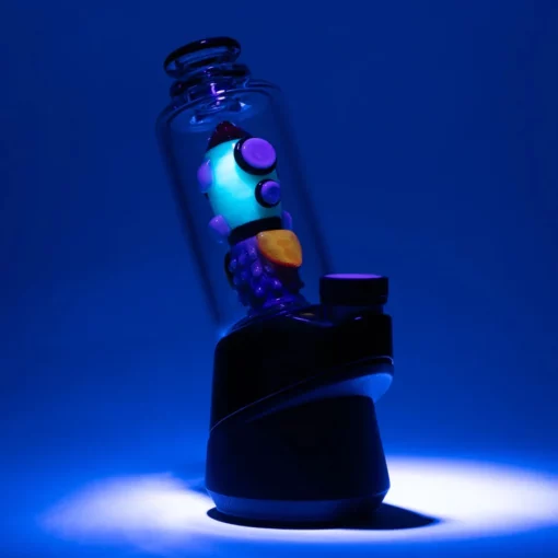 Empire Glassworks Glow Rocket Ship Peak Attachment, a 4½-inch US-made accessory designed to enhance your Puffco setup. This compact, glow-in-the-dark attachment features a whimsical rocket ship design, showcasing vibrant colors and intricate detailing that adds a playful yet functional aesthetic to your cannabis collection. Perfect for those who appreciate unique and artistic smoking accessories, available exclusively at Cannabox.